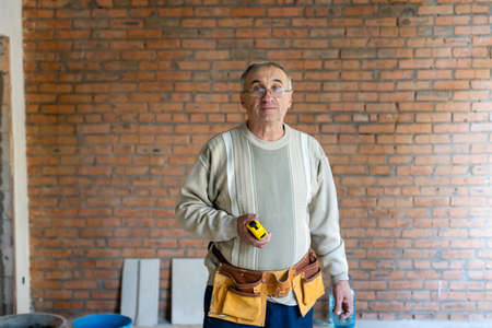 elderly worker with tape measure at construction siteの写真素材