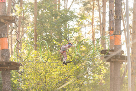 Girl climbing in adventure park is a place which can contain a wide variety of elements, such as rope climbing exercises, obstacle courses and zip-lines.の写真素材