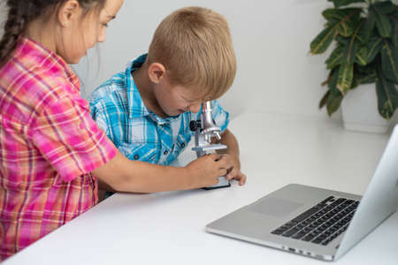renewable energy, children, technology, science and people concept - kids or friends with laptop computer and microscope modelの写真素材