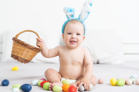 happy baby child with Easter bunny ears and colorful eggsの写真素材
