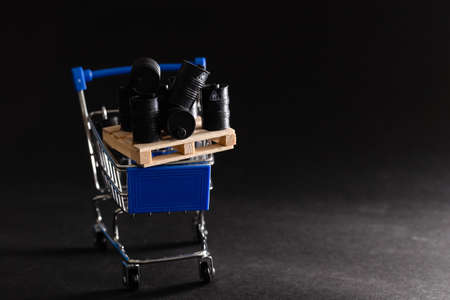 Small shopping cart and barrels isolated on dark backgroundの写真素材