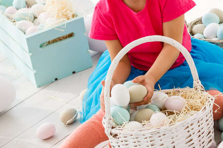 Getting ready to Easter. Lovely little girl holding an Easter egg and smiling with decoration in the backgroundの写真素材