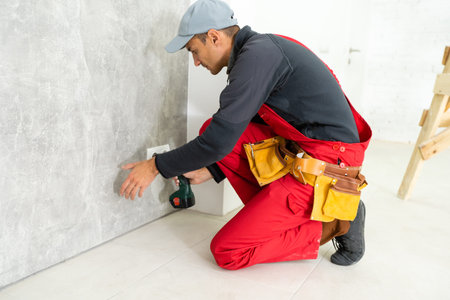 Electrician working at plug socket in the building