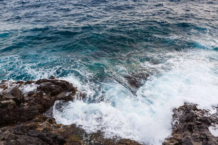 ocean waves hit and crash against stonesの写真素材