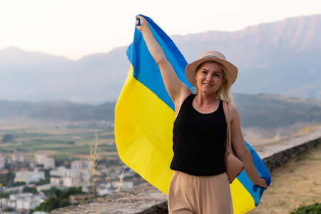Happy woman with flag of Ukraine staying in the mountains