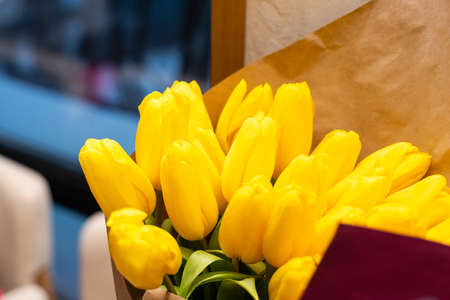 A bouquet of yellow tulips in a vase on the floor. A gift to a womans day from yellow tulip flowers. Beautiful yellow flowers in vase by wall.の写真素材