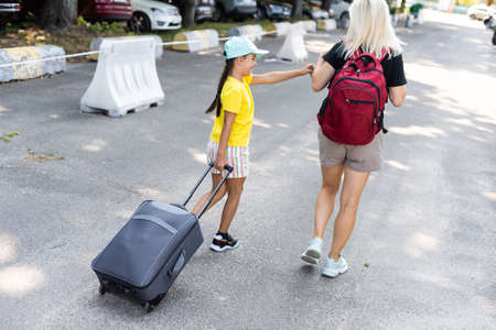 mother and daughter with suitcase in the parking lotの写真素材