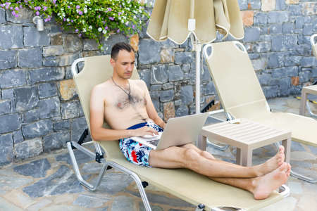 man using a laptop near the poolの写真素材