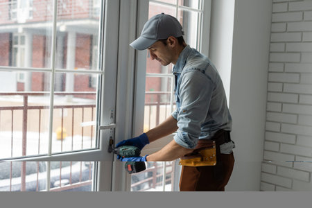 handyman adjusting white pvc plastic window indoors. worker using screwdriver to repair upvc window....