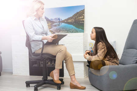 Communication session of school psychologist and girl 9, 10 years. Child tells psychotherapist his experiences, mental health of children.の写真素材