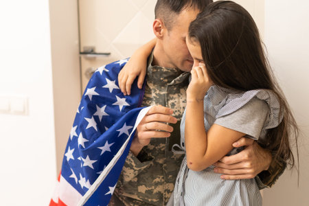 a child girl hugs a military father. dad in military uniform with his daughter. the veterans return to the familyの写真素材