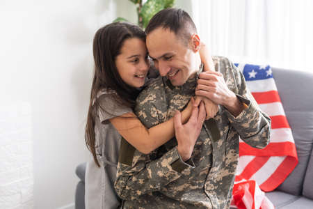 Little child is very happy her father came back from army. Little kid is hugging her father.の写真素材