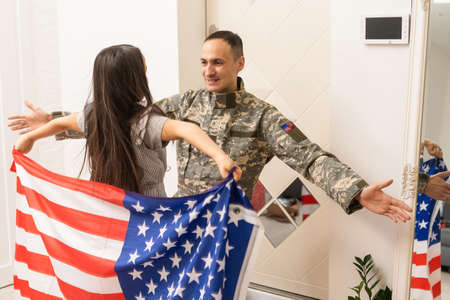 Soldier with flag of USA and his little daughter hugging, space for textの写真素材