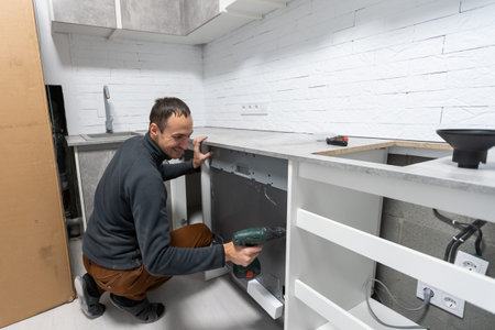 Young Repairman Service Worker Repairing Dishwasher Appliance In Kitchen.