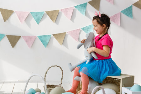 Getting ready to Easter. Lovely little girl holding an Easter egg and smiling with decoration in the backgroundの写真素材