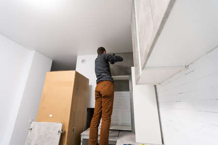 furniture assembly - worker installing cabinet shelfの写真素材