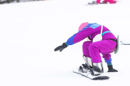 little cute girl learning to ride a childrens snowboard, winter sports for the child, safety of active sports.の写真素材
