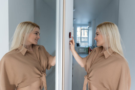 Side view pleasant young woman using smart home system or activating modern alarm system before...