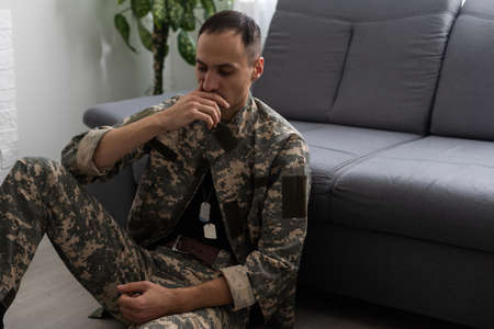 Nervous male military suffering depression, sitting alone at home, PTSD conceptの写真素材