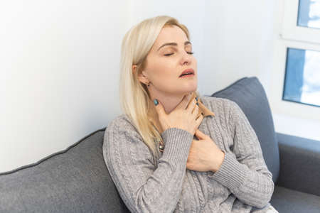 Attractive woman s sitting on bed with sore throatの写真素材
