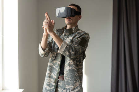 Military man trying to touch virtual objects while wearing a VR headset. Disability and modern gadgets.の写真素材