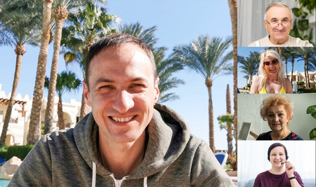 man headphones is sitting in front of a laptop monitor on the beach with palm trees