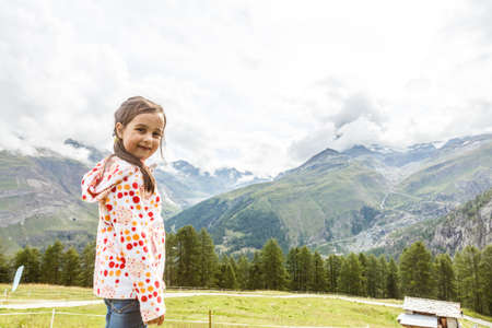 Children hiking in Alps mountains. Kids look at snow covered mountain. Spring family vacation. Little girl on hike trail in alpine meadow. Outdoor fun and healthy activity.の写真素材