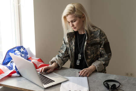 Young female soldier working with laptop in headquarters building.の写真素材