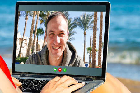 Cheerful Young Man Working Remotely from the beach With Laptopの写真素材