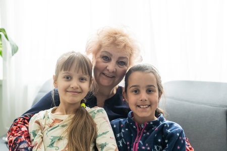 Smiling loving mature grandmother and two granddaughters. Family holiday and togetherness.