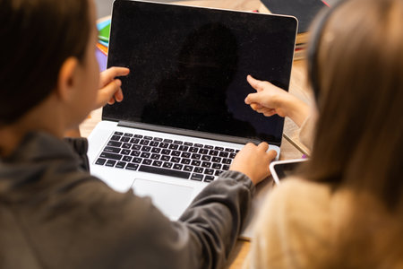 Pretty teen girl point to laptop screen and her younger sister look feel surprise.