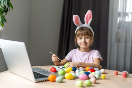 Little girl with her bunny using computer together preparing for easter