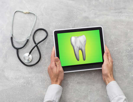 Discussing issues. Cropped shot of a professional dentist showing jaws and teeth x-rays to his patient using a digital tabletの写真素材