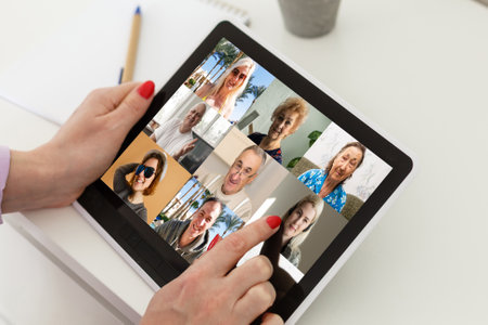 Remote Work Communication. Businesswoman Holding Tablet Having Online Meeting With Group Of Coworkers Making Video Call Via Computer Sitting In Modern Office. Selective Focus, Croppedの写真素材