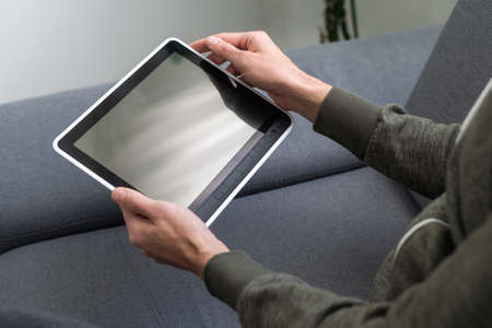 hands of a man holding blank tablet device.