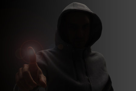 Close up portrait of a courageous man in a deep dark hood on a black background. The concept of...
