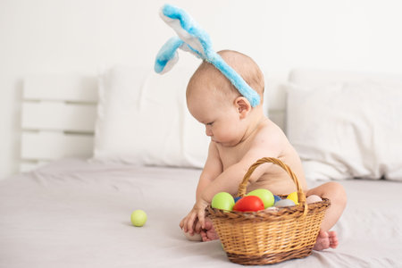 Portrait of a cute baby dressed in Easter bunny ears with a basket full of eggs