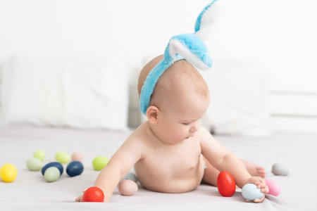 happy baby child with Easter bunny ears and colorful eggs