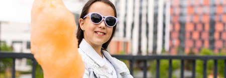 Adorable little girl eating candy-floss outdoors at summerの写真素材