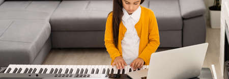 Little girl watching online lesson tutorial how to learn a synthesizerの写真素材