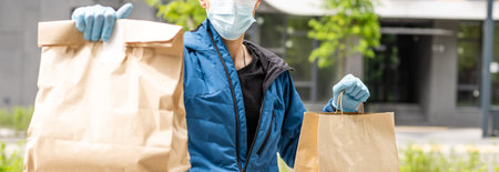 Hispanic young delivery man wearing face mask while carrying parcel box during coronavirus outbreak.