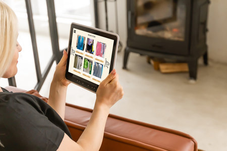 Back view of woman doing shopping online on website with digital tablet at home. Top view of lady on...