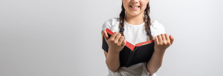 Smart little schoolgirl with book. Child in an elementary school. Education and learning for kids.