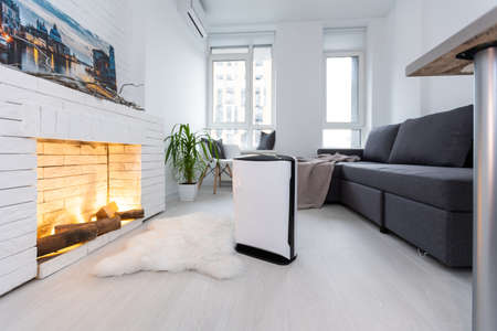 Air purifier in cozy white bedroom for filter and cleaning removing dust PM2.5 HEPA and virus in home for fresh air and healthy Wellness life, Air Pollution Conceptの写真素材