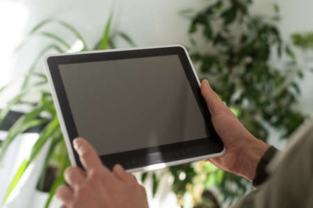 Digital tablet computer with isolated screen in male hands over cafe backgroundの写真素材