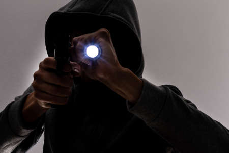 Studio portrait of a man in a hood, a shadow hides his face. Anonymity shadow economy and evasion from the lawの写真素材