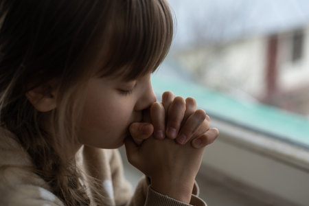 Praying little girl near windowの写真素材
