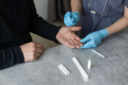 Nurse performing a coronavirus pcr test on an elderly man in his homeの写真素材