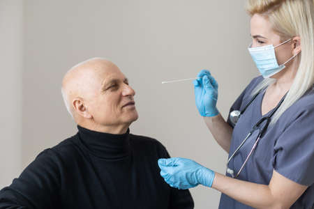Nurse performing a coronavirus pcr test on an elderly man in his homeの写真素材