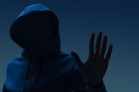 Close up portrait of a courageous man in a deep dark hood on a black background. The concept of...